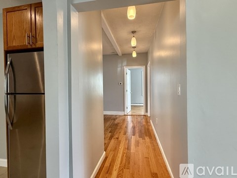 A kitchen with a refrigerator and wooden cabinets.