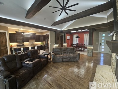 A living room with a black leather couch and a fireplace.