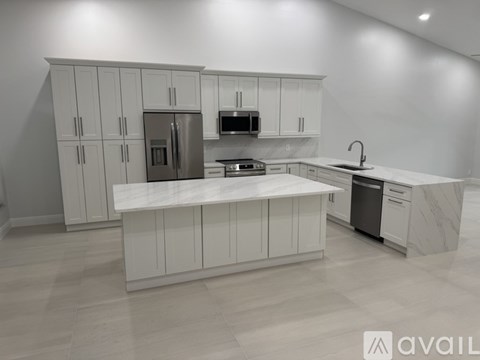A kitchen with white cabinets and a marble countertop.