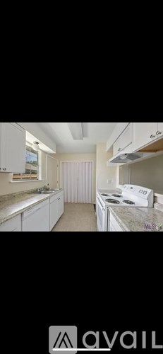 A kitchen with white cabinets and a marble countertop.