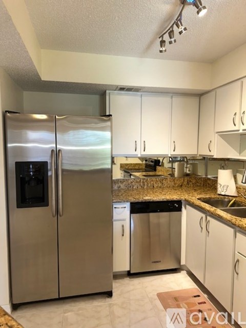 A kitchen with a stainless steel refrigerator and white cabinets.
