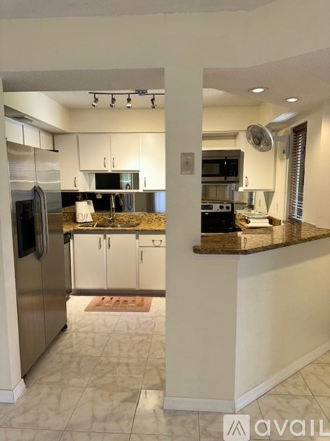 A kitchen with a refrigerator, microwave, and oven.