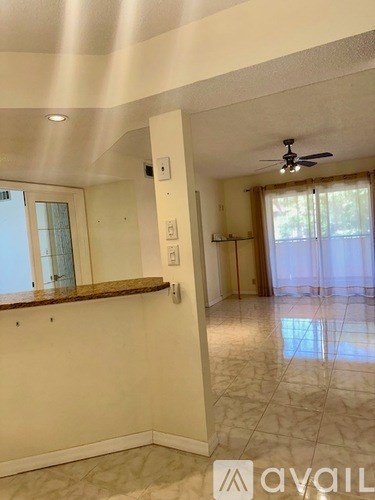 A spacious room with a ceiling fan and a window with a view of the outdoors.
