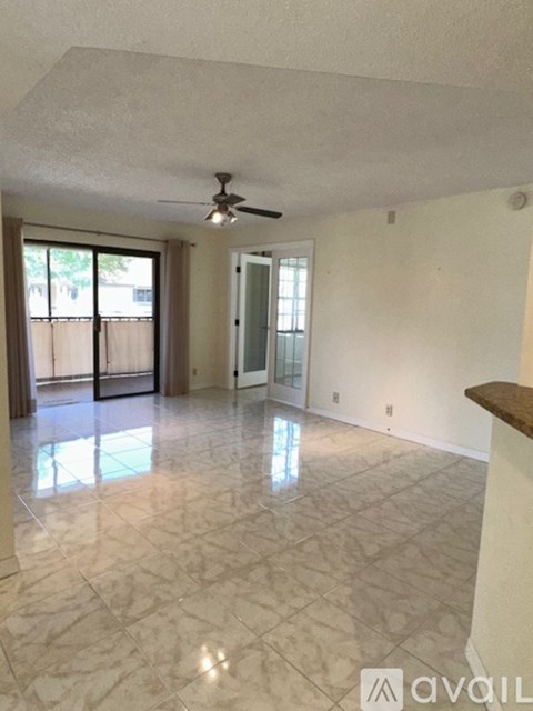 A spacious room with a marble floor and a ceiling fan.