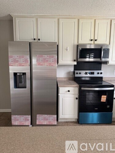A kitchen with a fridge, oven, and microwave.