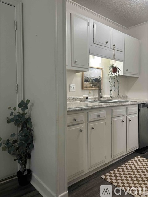 A kitchen with white cabinets and a checkered mat on the floor.