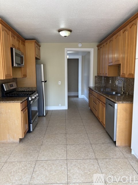 A kitchen with wooden cabinets and a tile floor.