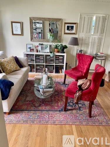 A living room with a red chair and a glass coffee table.