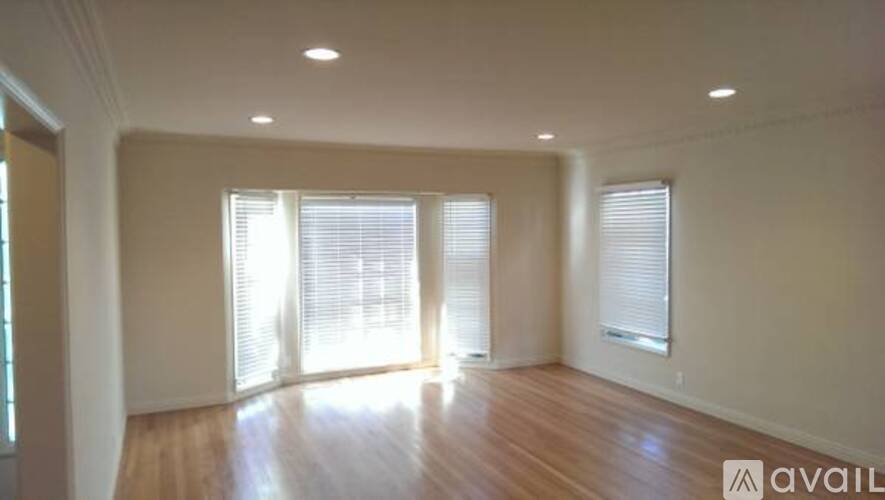 A spacious room with wooden floors and large windows.