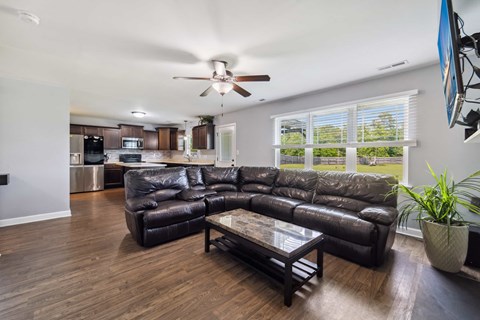 A black leather sectional sofa with a glass coffee table in the middle of a living room.