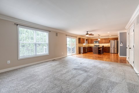 A spacious living room with a grey carpet and a ceiling fan.