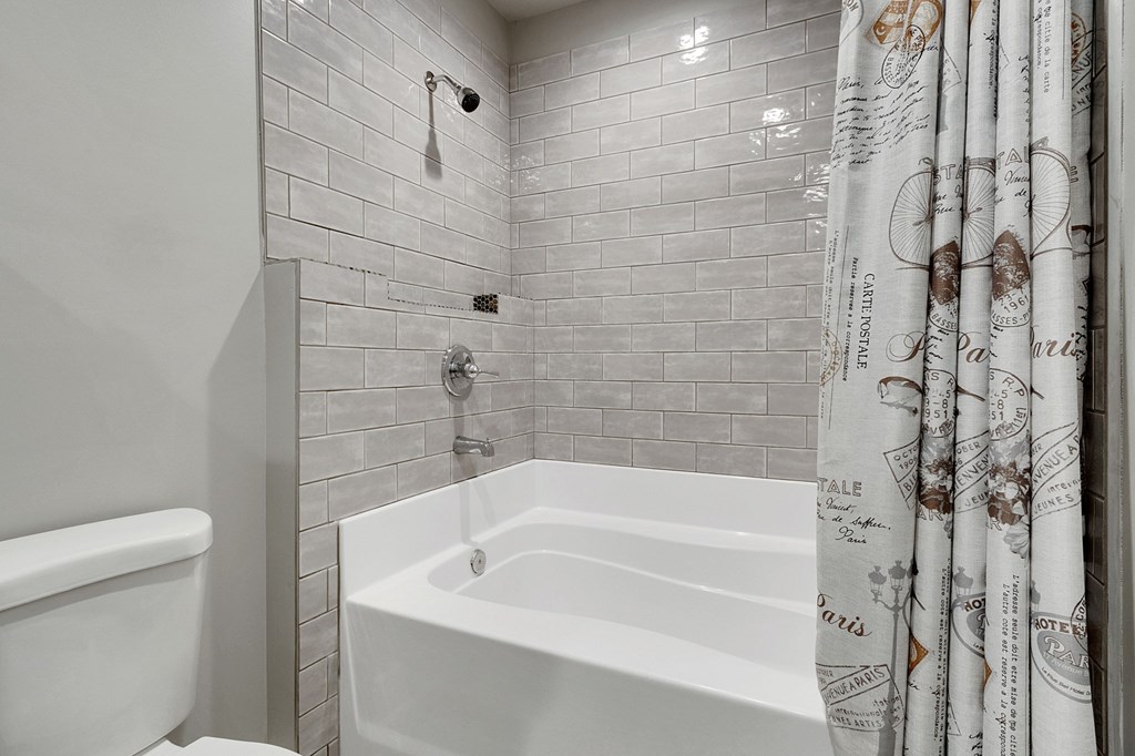 A white bathtub sits in a bathroom with a shower head and curtain.