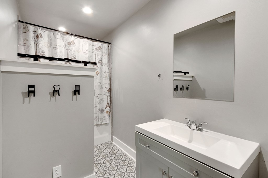 A bathroom with a white sink and a mirror.