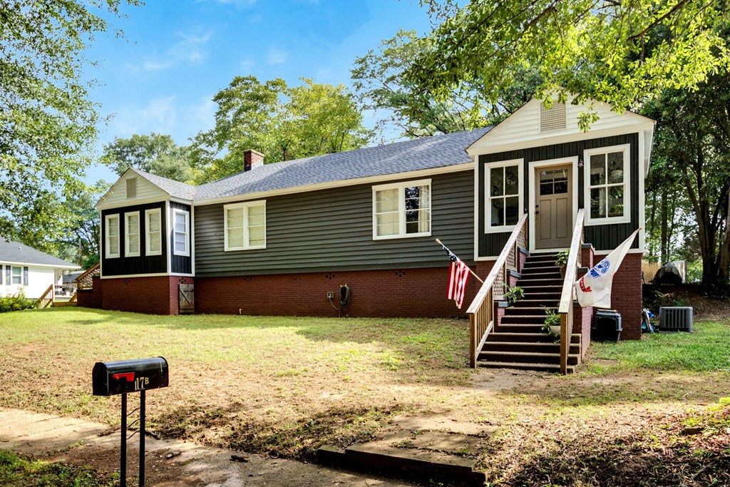 A house with a grey siding and a brown roof with a mailbox in front.