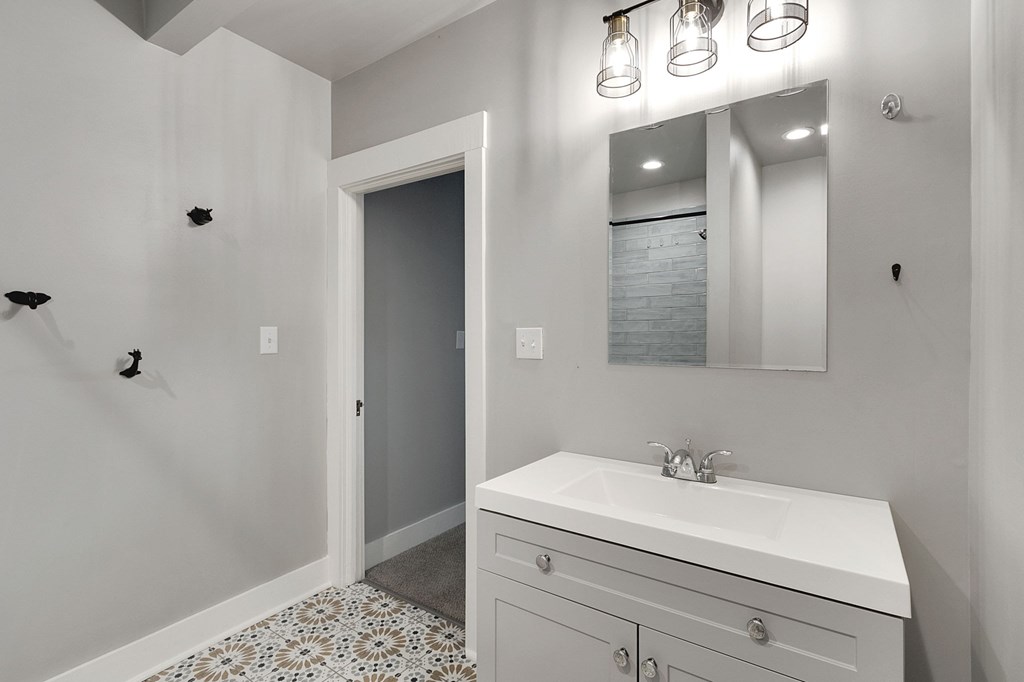 A bathroom with a white sink and a mirror above it.