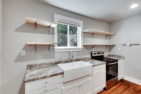 A kitchen with white cabinets and a marble countertop.