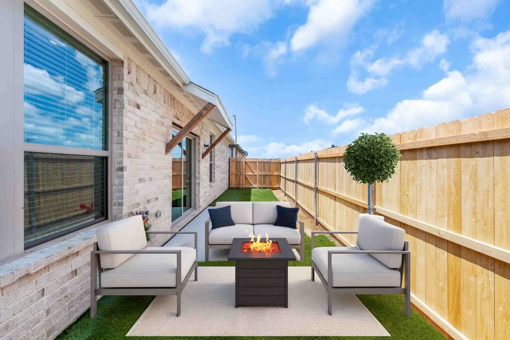 A patio with a fire pit and chairs.