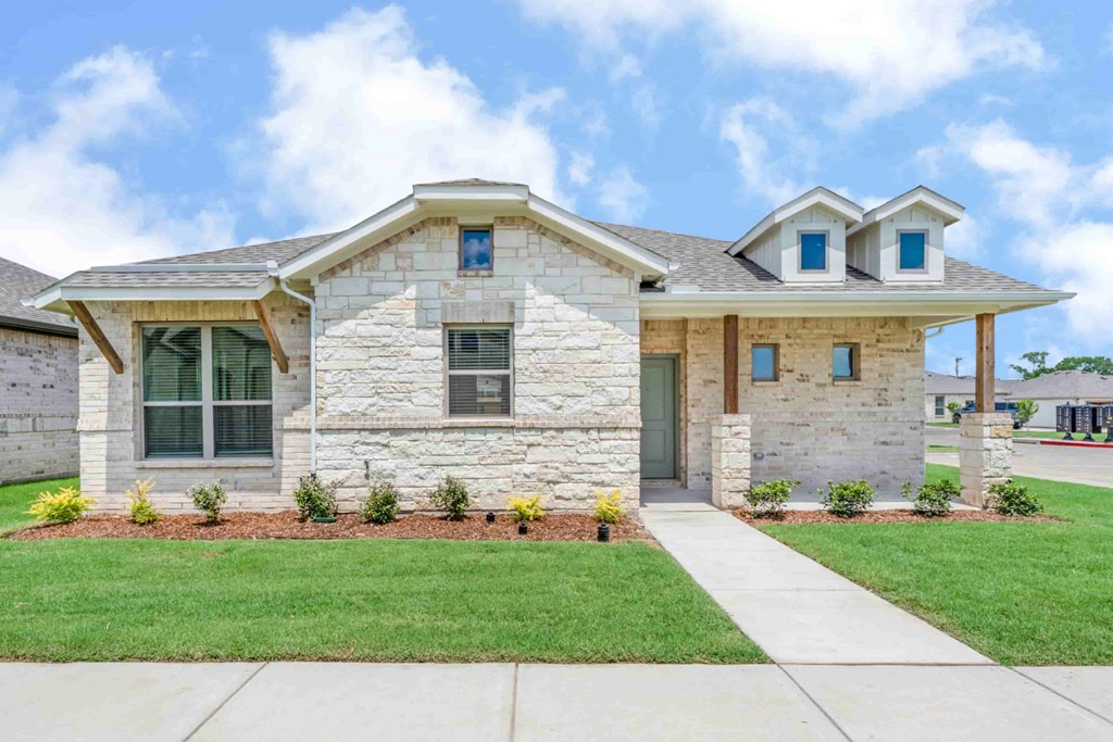 A house with a stone facade and a grey roof.