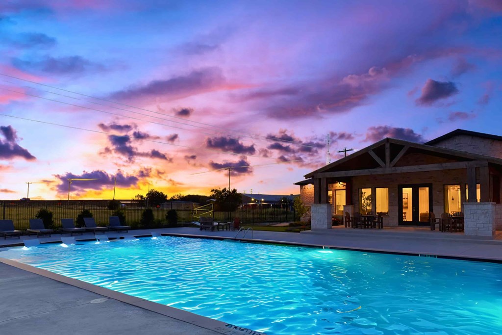 A pool with a house in the background during sunset.