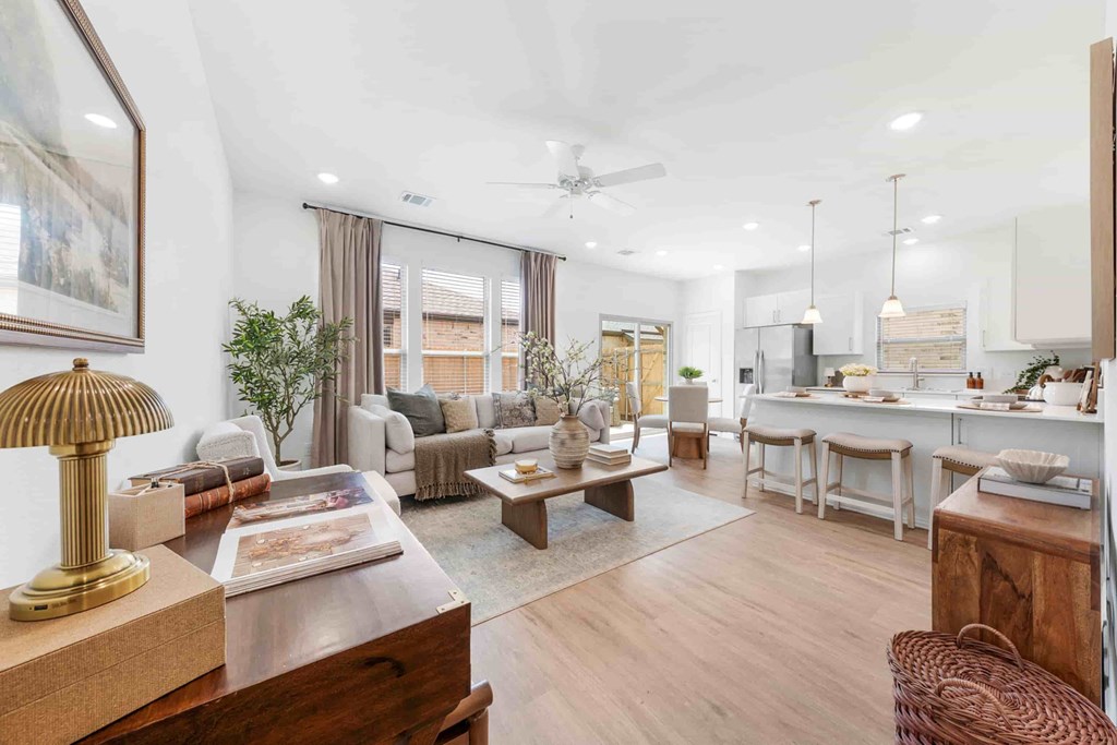 A well-lit, modern living room with a variety of seating options and a kitchen area in the background.