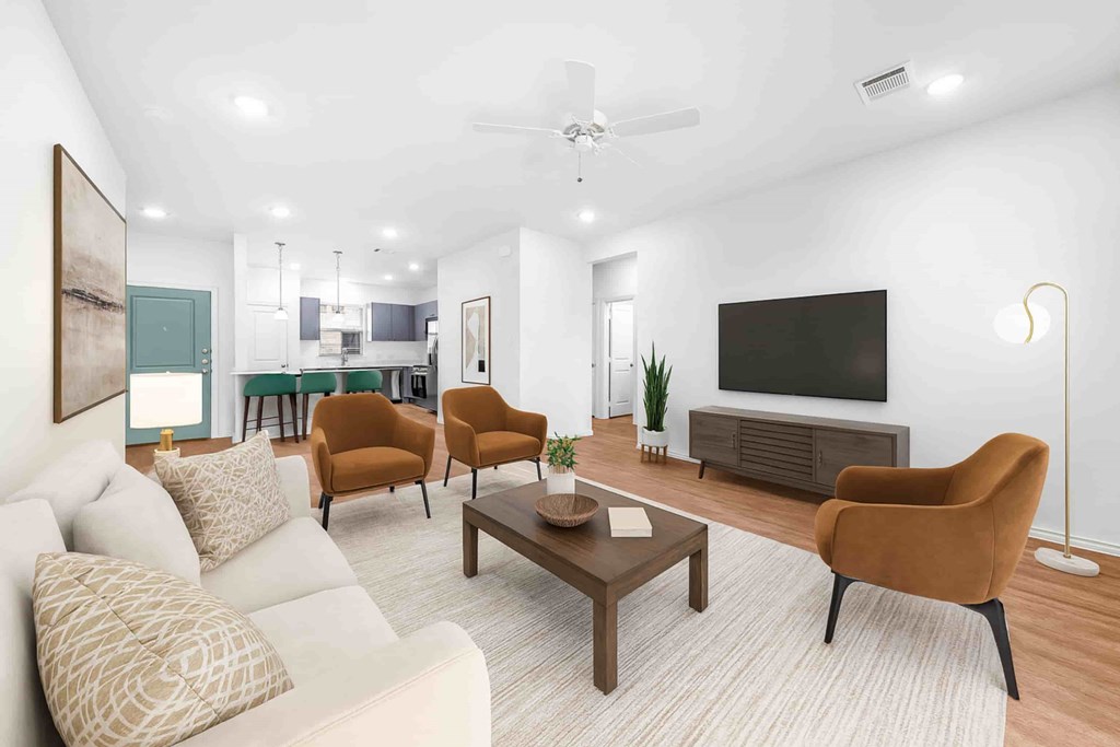 A living room with a white couch, a brown chair, a brown coffee table, and a flat screen TV mounted on the wall.