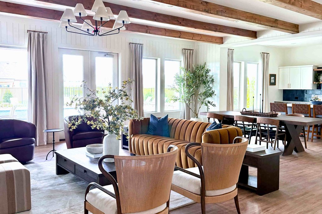 A living room with a brown sofa and wooden chairs.