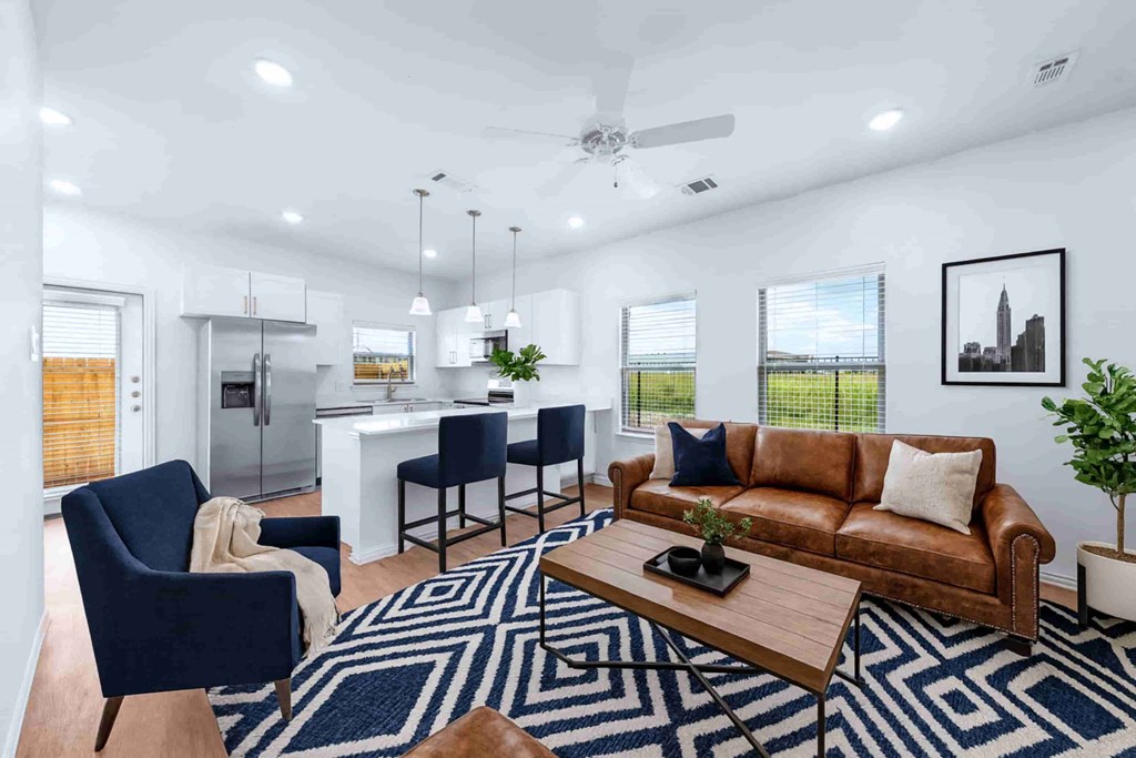 A modern living room with a brown leather couch and a blue patterned rug.