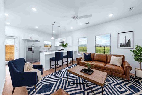 A modern living room with a brown leather couch and a blue patterned rug.
