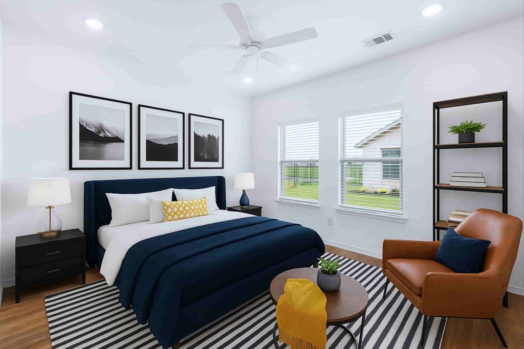 A bedroom with a bed, a chair, and a ceiling fan.