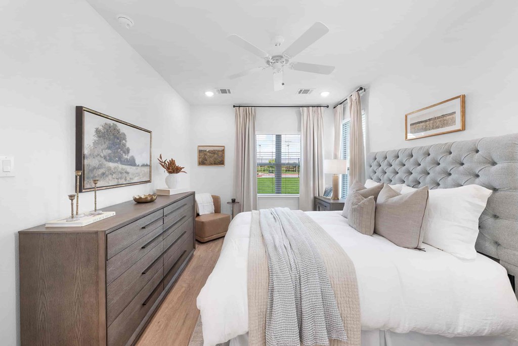 A bedroom with a large bed and a dresser with a painting on top.
