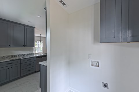 A kitchen with dark grey cabinets and a white wall.