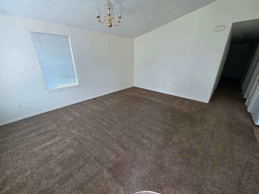 A room with a carpeted floor and a chandelier.