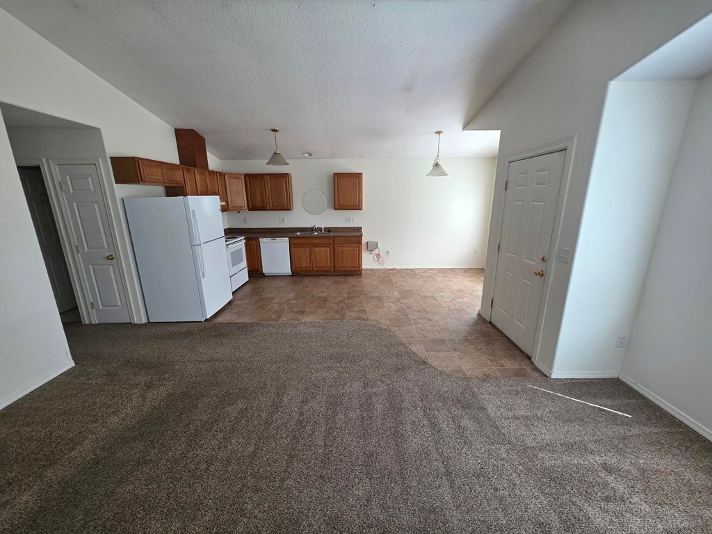 A kitchen with white appliances and brown cabinets.