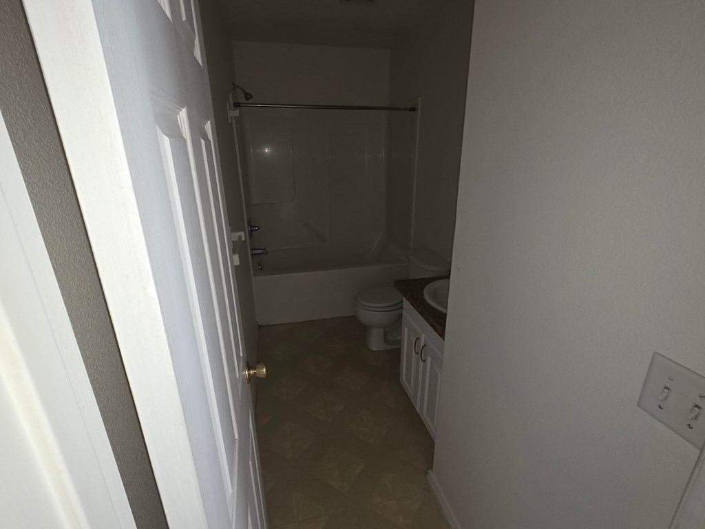 A small bathroom with a toilet, sink, and shower.