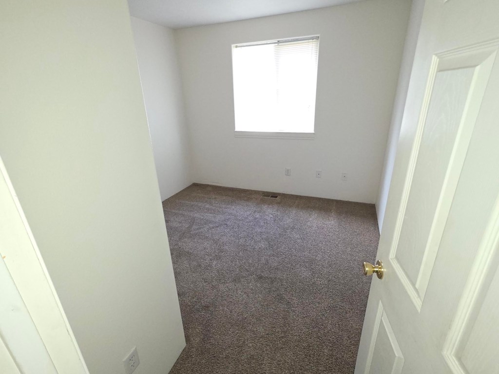 A room with a carpeted floor and a door.