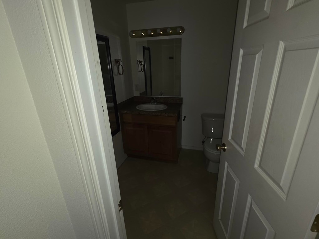 A bathroom with a toilet, sink, and mirror.