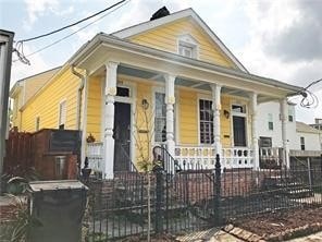 A yellow house with a black fence in front.