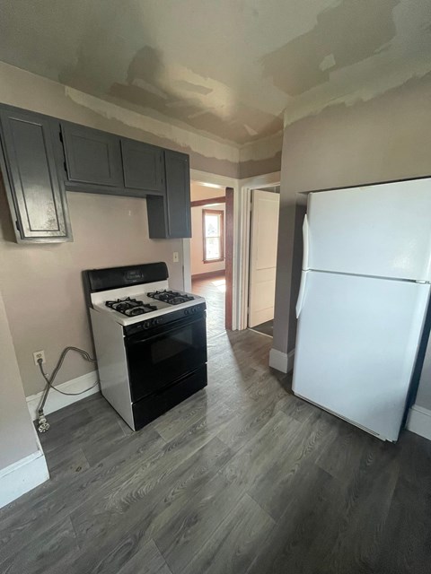 A kitchen with a white fridge and a black stove top oven.