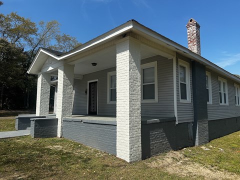 A house with a grey siding and a chimney on the roof.