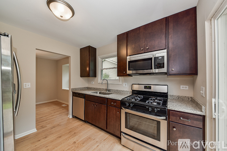 A kitchen with dark wood cabinets and stainless steel appliances.