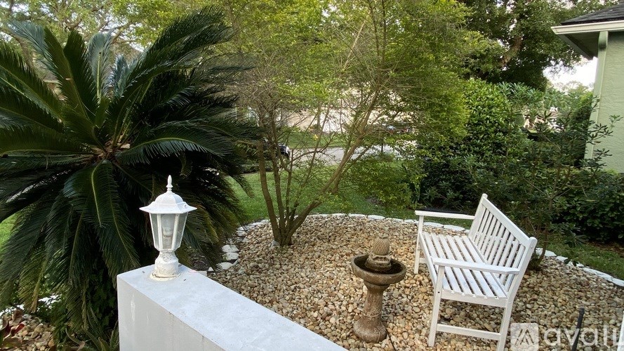 A white chair sits on a gravel area next to a white lamp post.