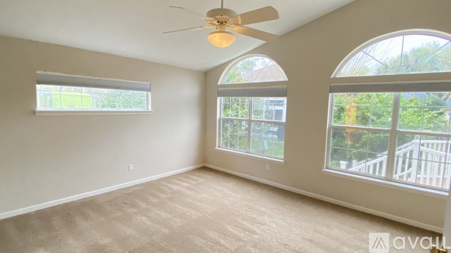 A room with a ceiling fan and two windows.