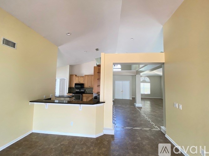 A spacious living room with a kitchen area in the background.