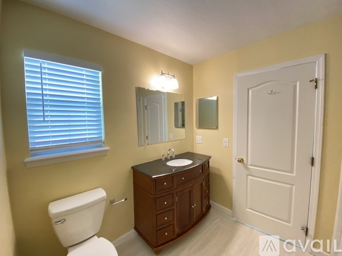 A bathroom with a toilet, sink, and mirror.