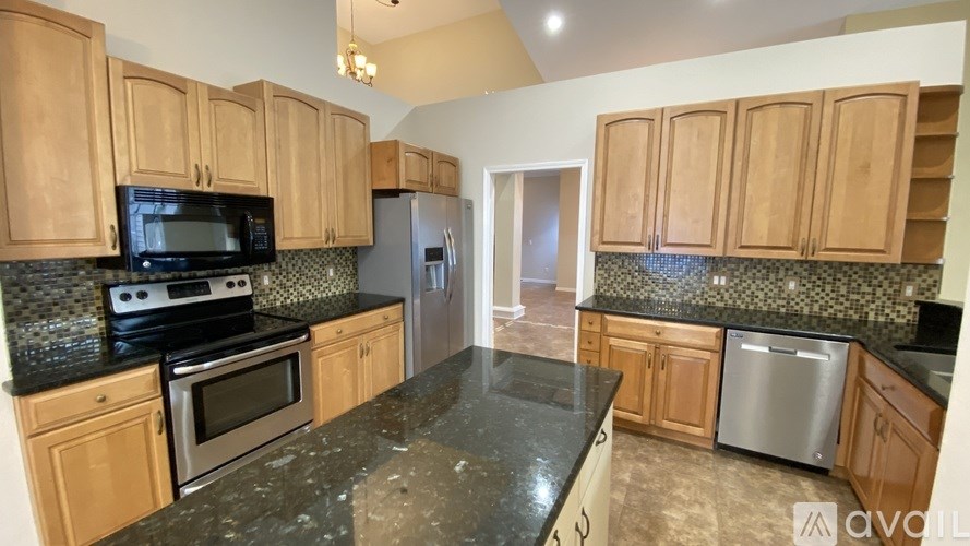 A kitchen with wooden cabinets and black countertops is available for rent.
