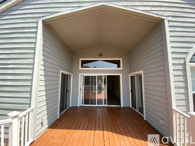 A deck with a white railing and a sliding glass door.