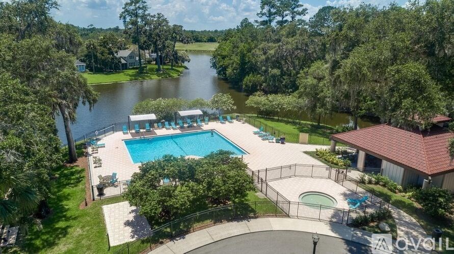 A large outdoor pool surrounded by a fence and trees.