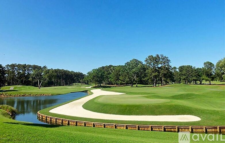 A golf course with a pond and trees in the background.