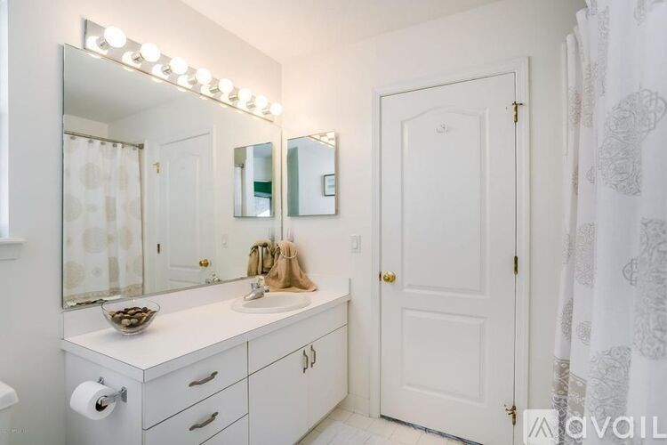 A bathroom with a white sink and a mirror with lights on it.