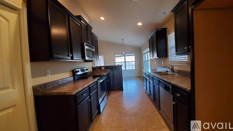 A kitchen with black cabinets and brown countertops.